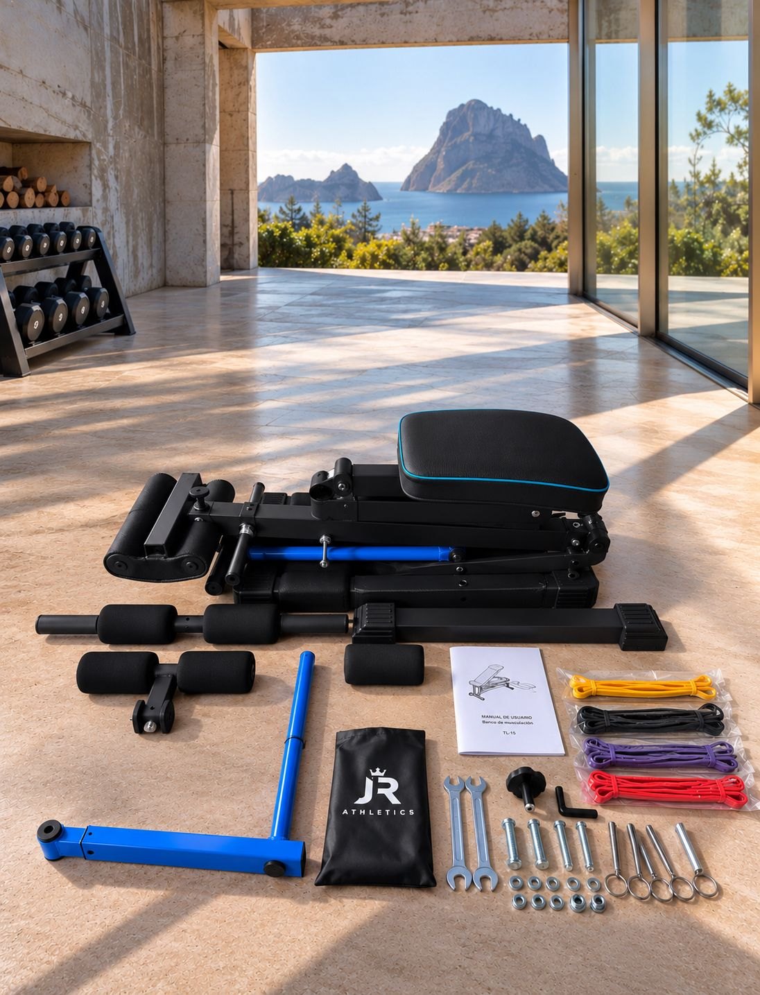 Todo el contenido de la caja del TX-11 colocado en el suelo: el banco plegado y sus piezas, las cuatro bandas, la bolsa con el logo JR ATHLETICS, el manual, las herramientas y la tornillería